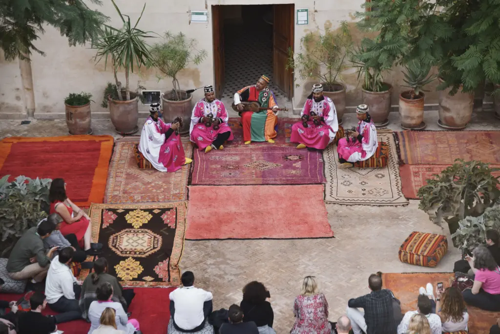 A group of travelers gathered in an ornate Moroccan riad courtyard
